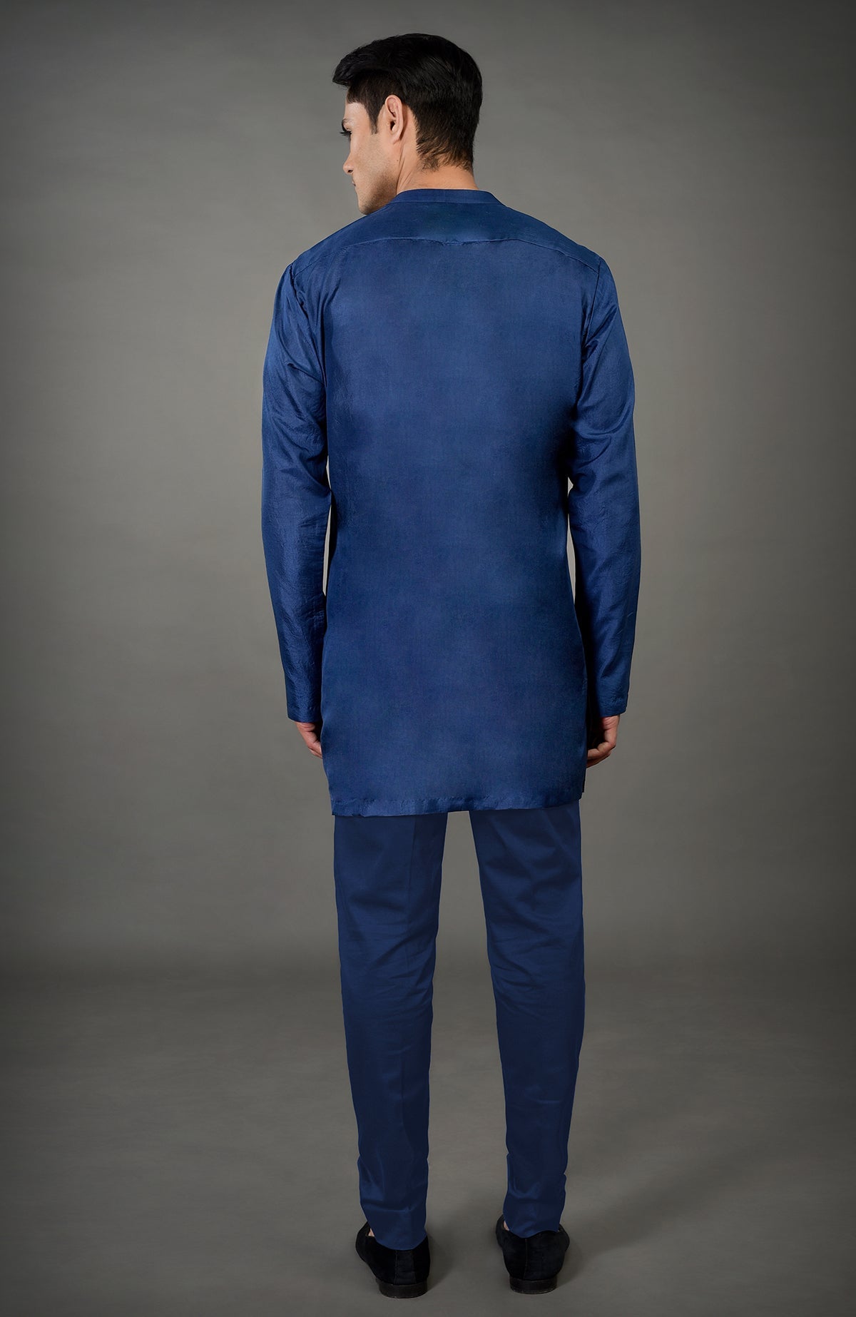 A man from behind wears a navy blue chikankari embellished jacket set.