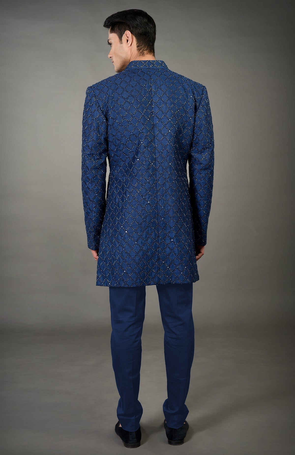 Man in a navy blue chikankari embellished jacket set with matching pants.