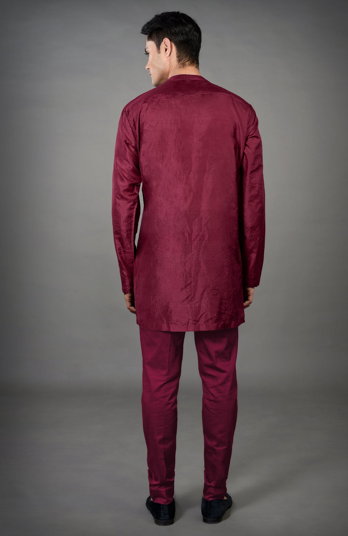 A man from the back wears a maroon chikankari embellished jacket set with black shoes.