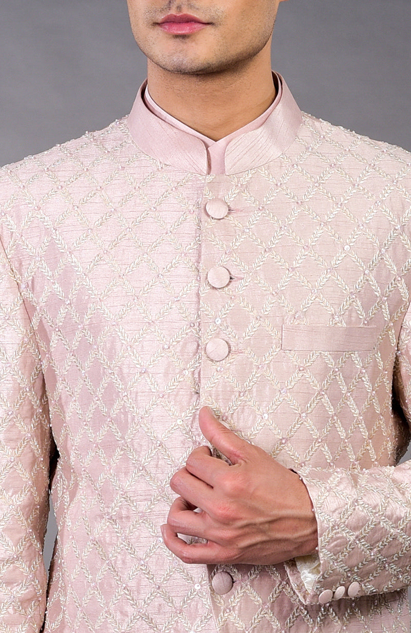 A man wears a barely pink chikankari embellished bandhgala jacket with an angarkha kurta.