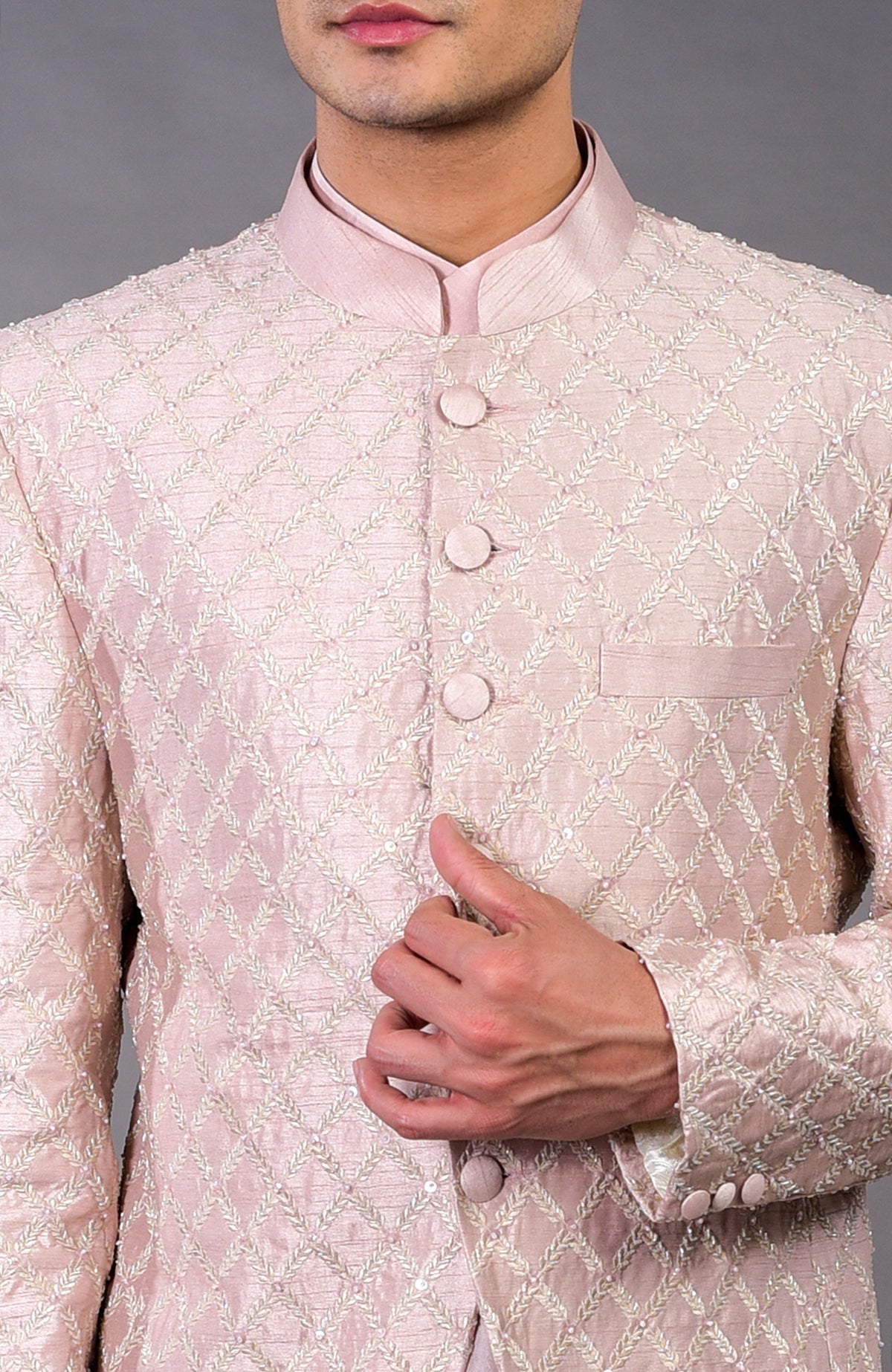 Barely pink chikankari embellished bandhgala set with a man's hand on the jacket.