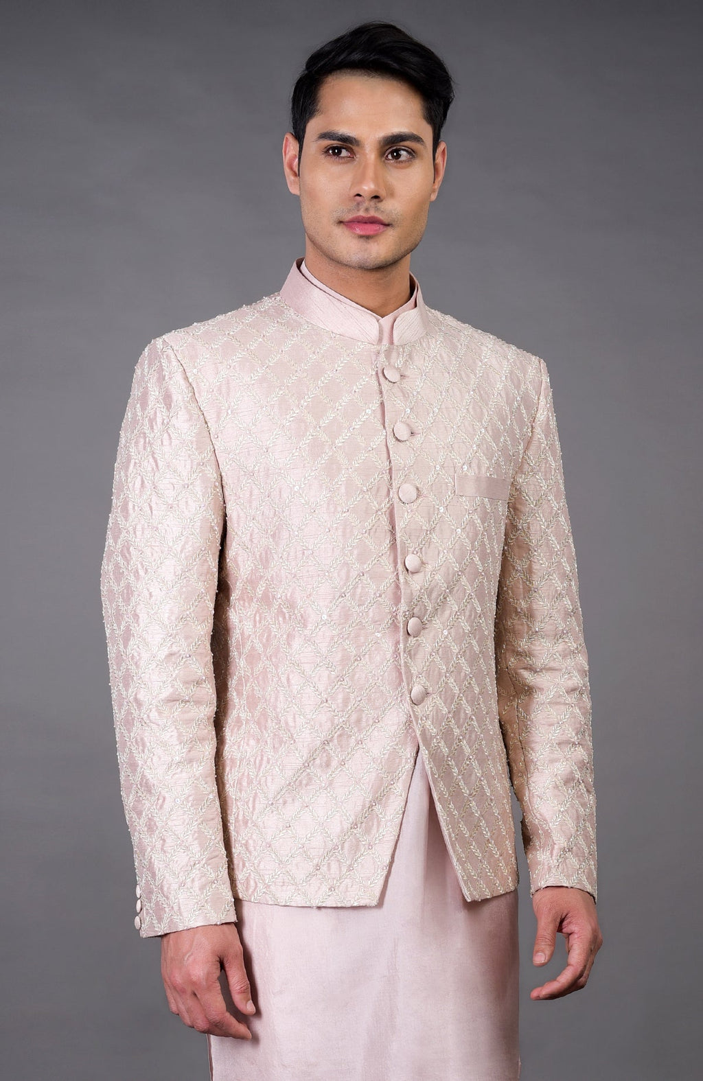 A man models a barely pink chikankari embellished bandhgala set.