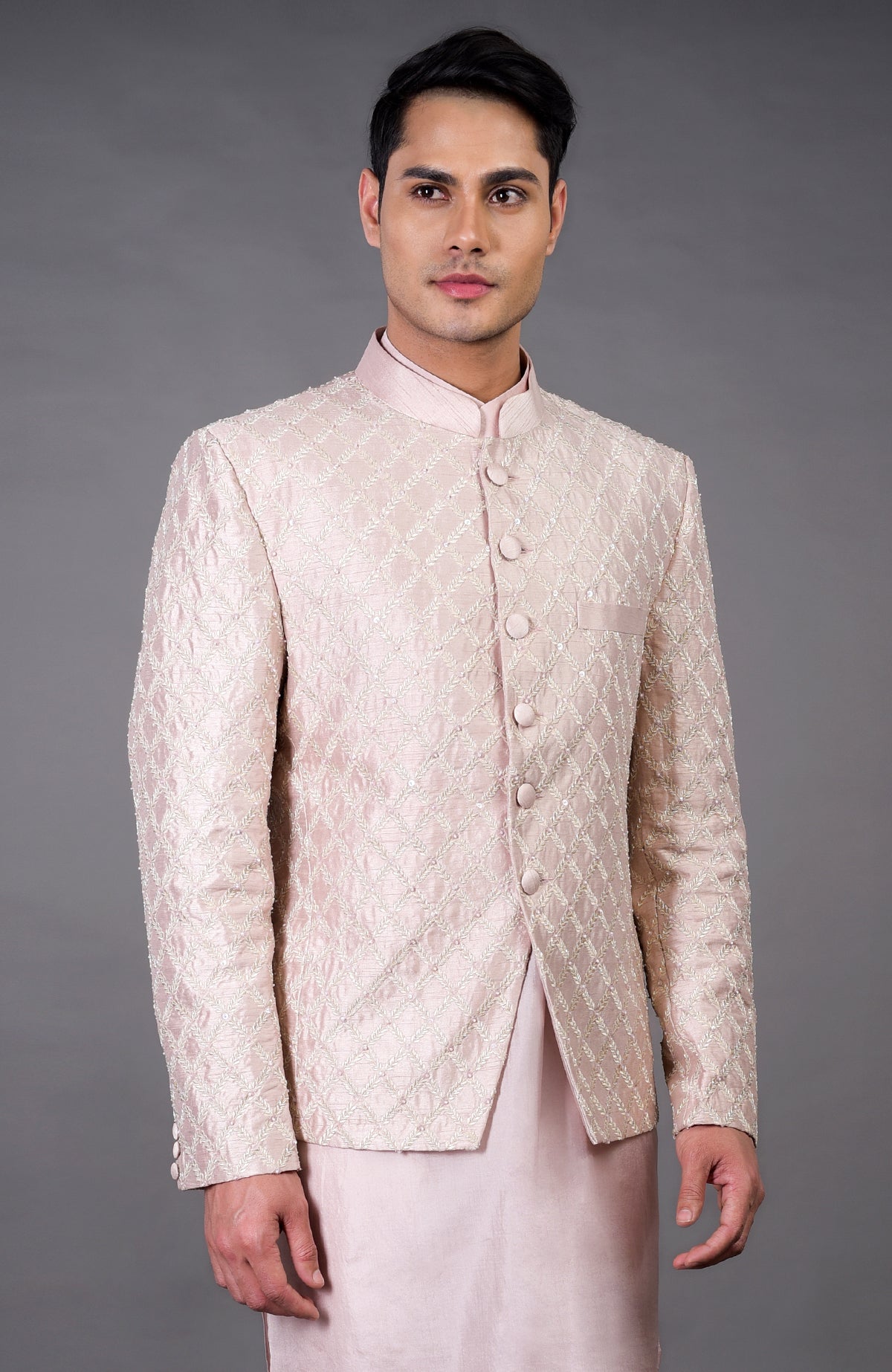 A man models a barely pink chikankari embellished bandhgala set.
