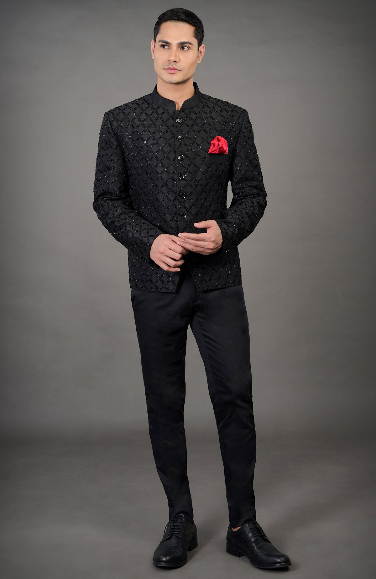A man models a black chikankari embellished jacket set with a red pocket square.