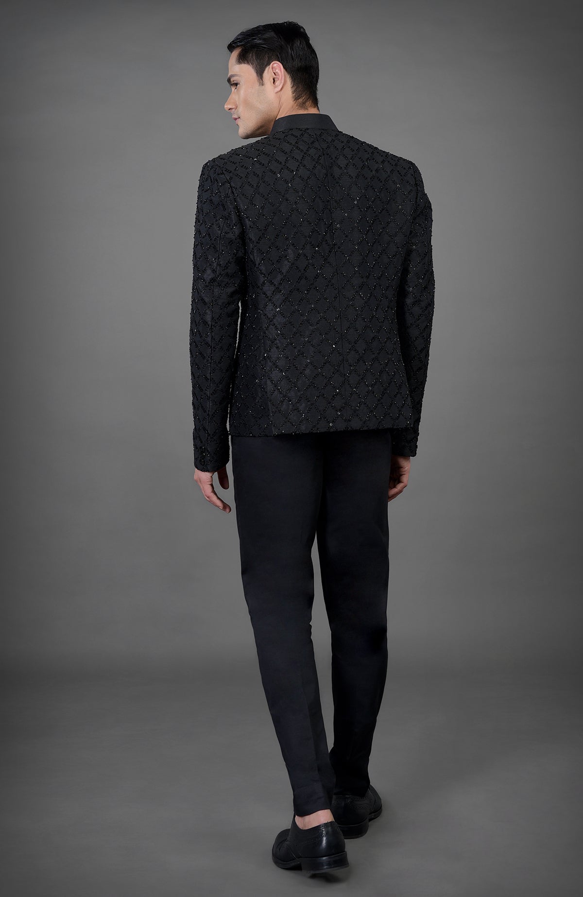 A man from behind wearing a black chikankari embellished jacket set.