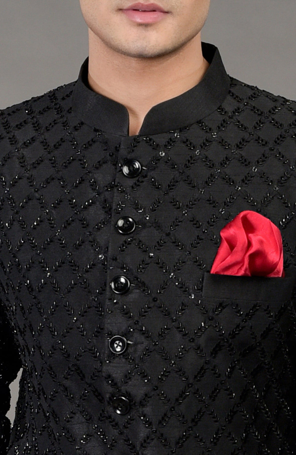 A man wears a black chikankari embellished jacket with a red pocket square.