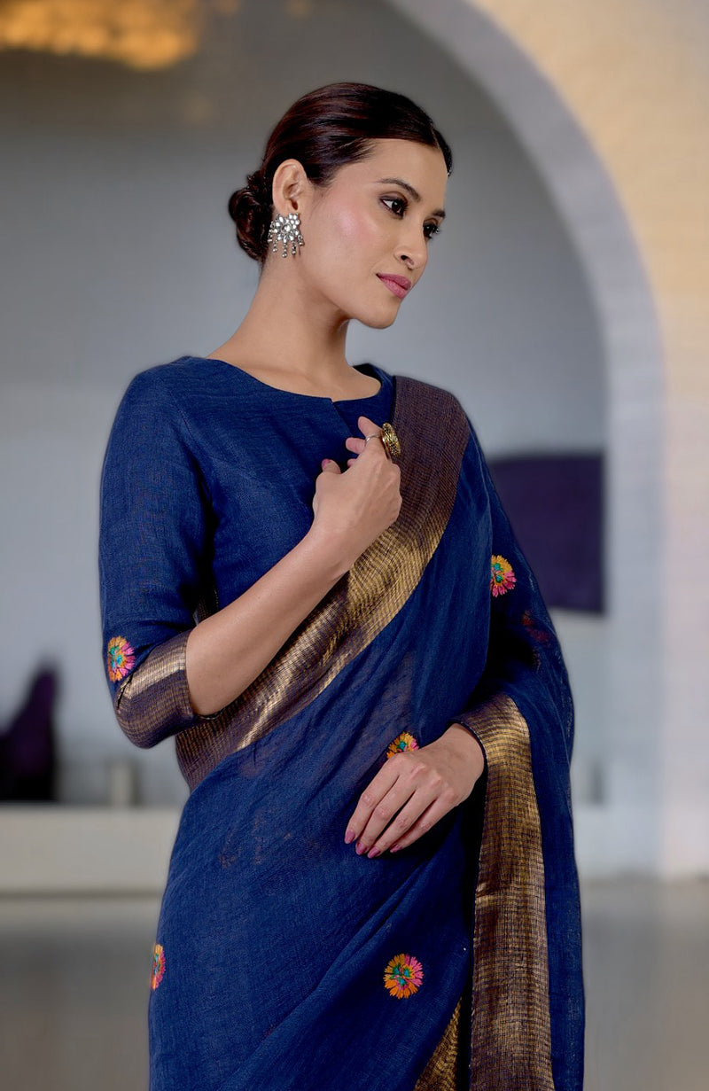 Navy blue linen saree with Kashidakari embroidery and gold zari border, paired with a matching blouse.