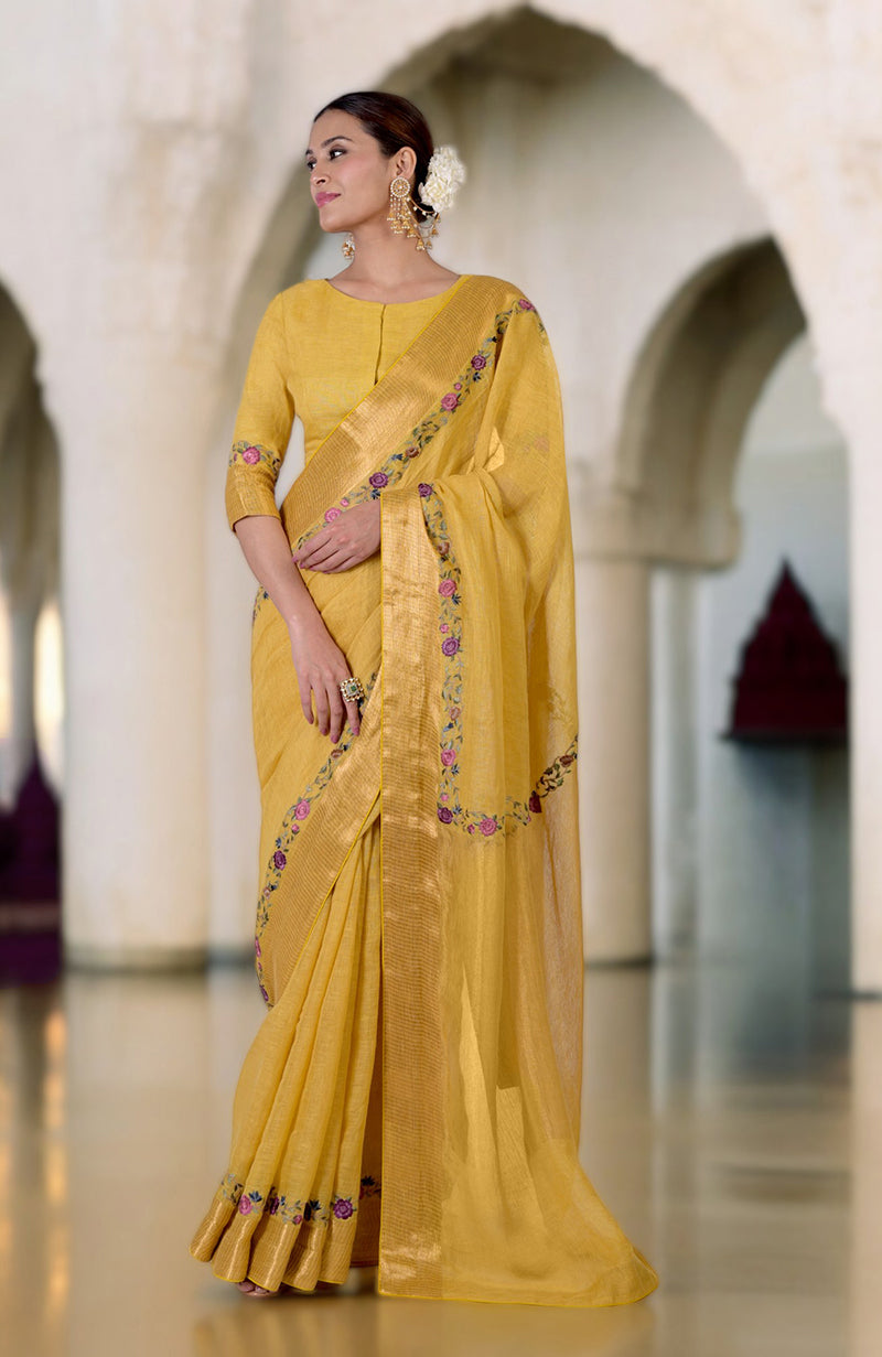 A woman in a yellow linen saree with Parsi Gara embroidery and zari details.