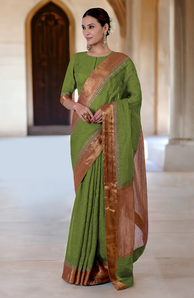 A woman models a green linen saree with gold embroidered borders.
