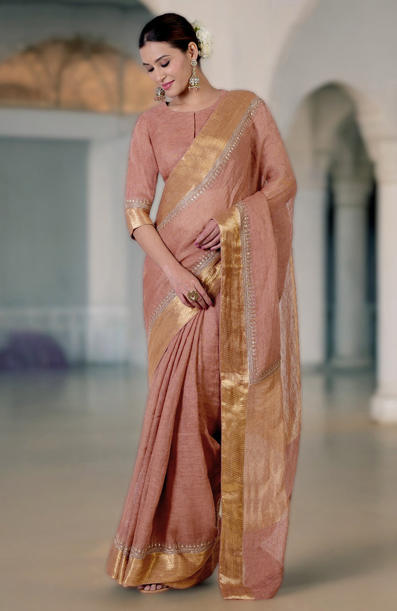 A woman models a chutney-colored linen saree with gold marori embroidered borders.