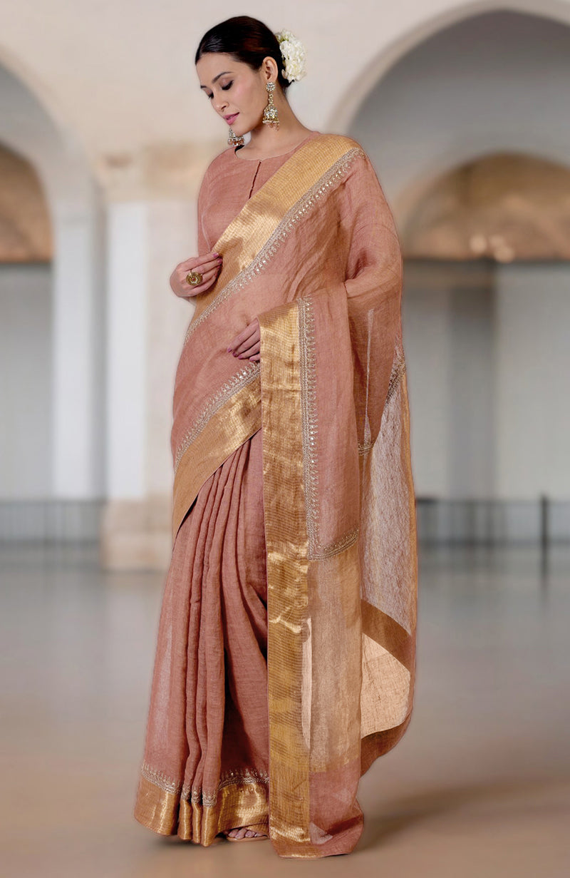 A woman models a chutney-colored linen saree with gold marori embroidered borders.