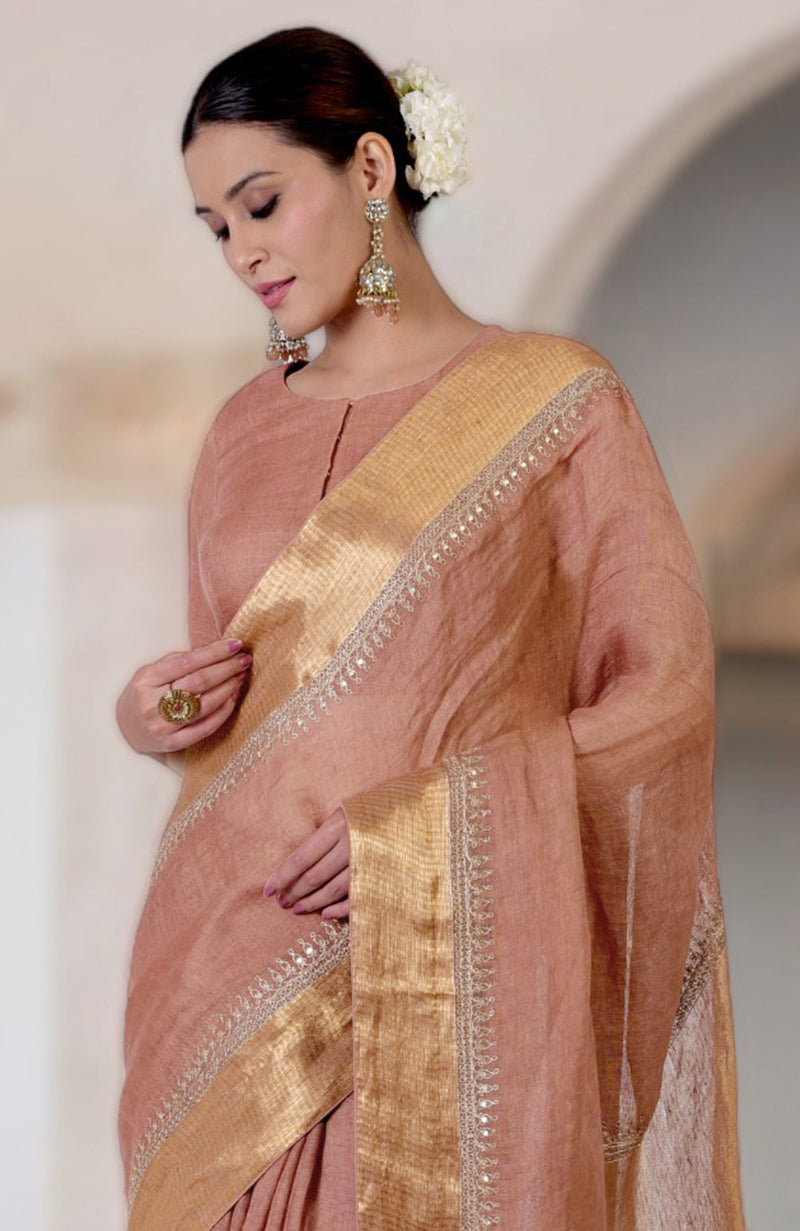 A woman in a chutney marori embroidered linen saree with gold borders.