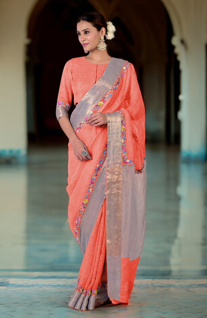 A woman models a peach linen saree with a gray and embroidered border.