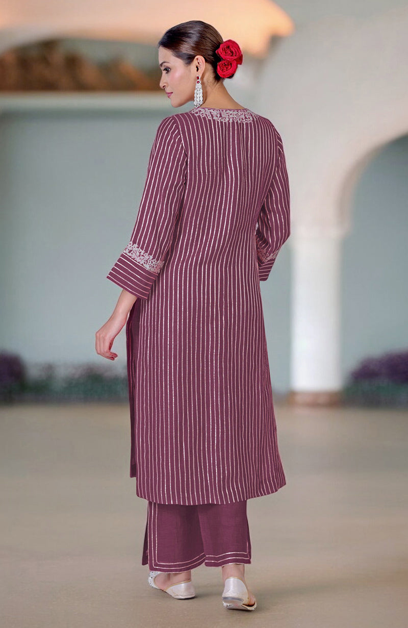 A woman in a burgundy purple striped kurta and matching pants stands with her back to the camera.
