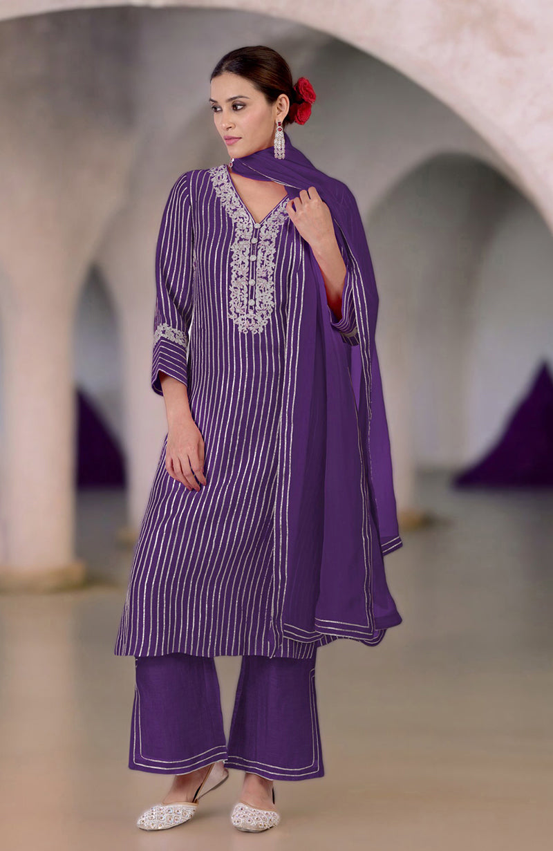A woman models a purple silk linen suit with silver embroidery and gota work.