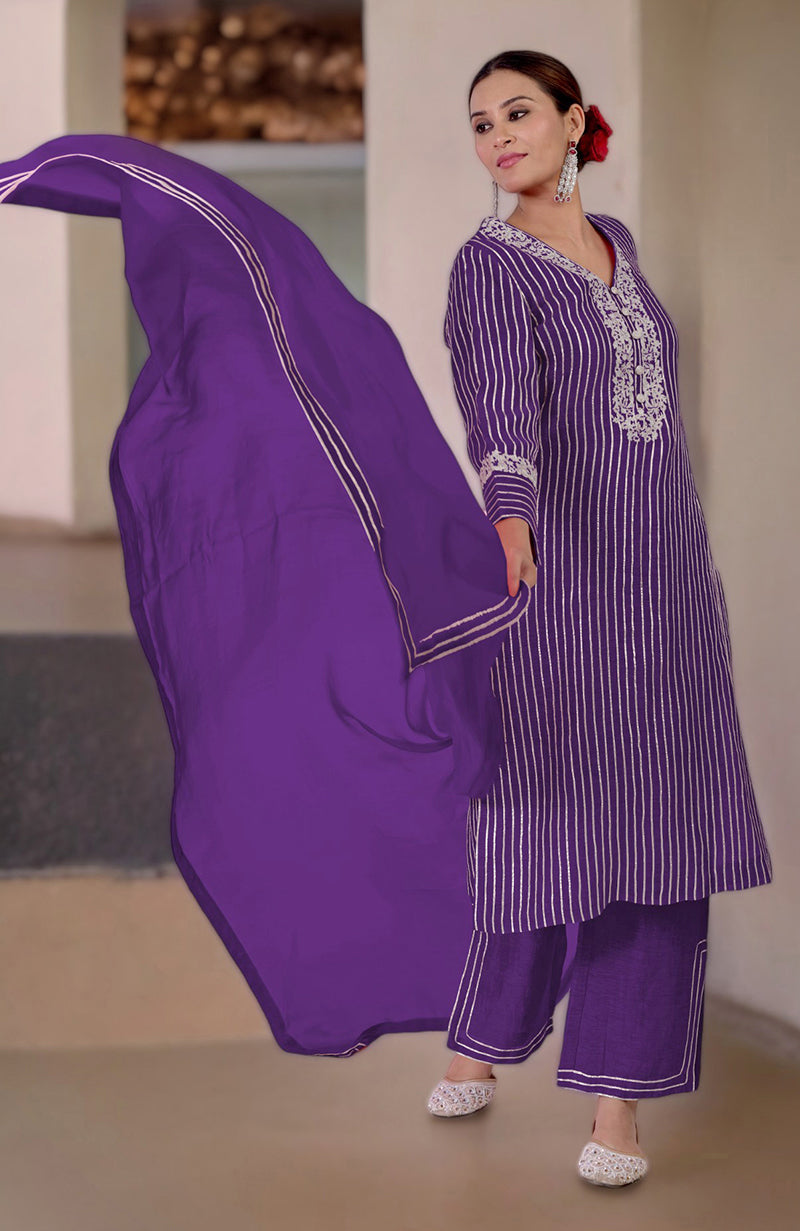 A woman models a mulled grape silk linen suit with gota and tilla embroidery.