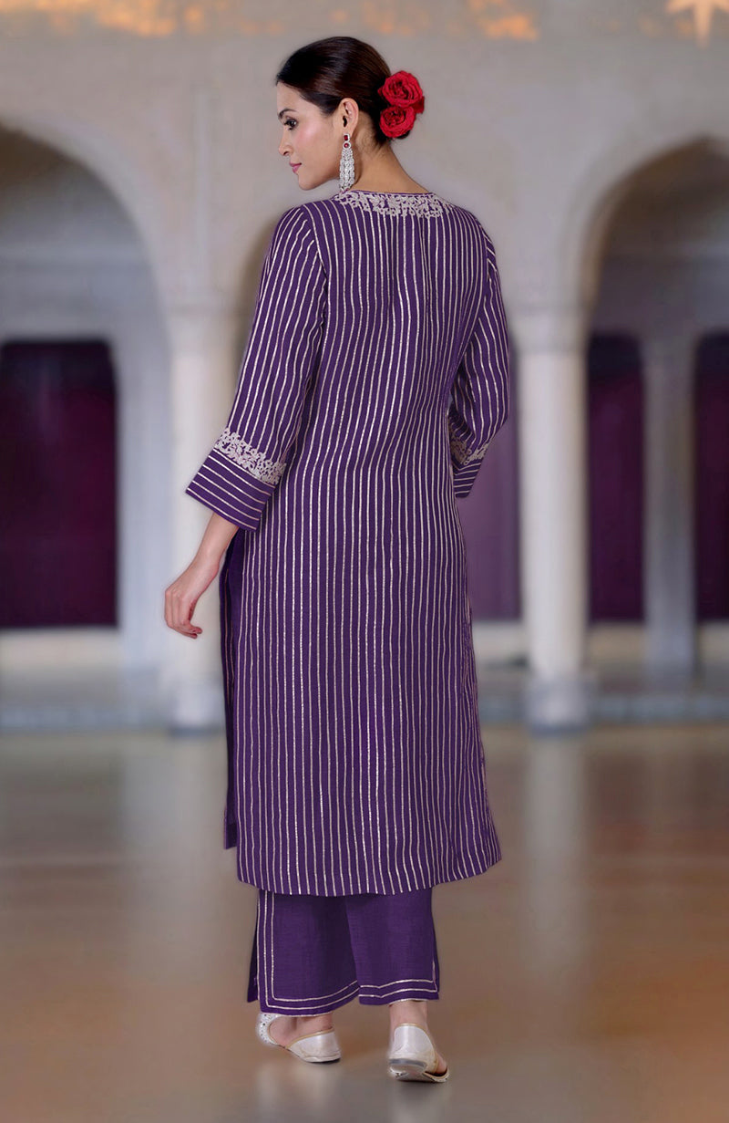A woman in a purple striped kurta and pants with silver embroidery.