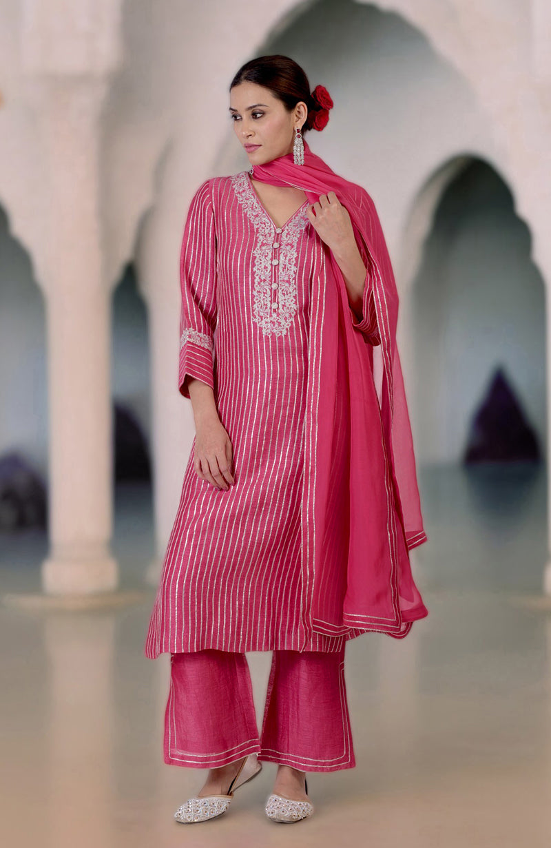 A woman models a pink silk linen suit with silver embroidery and a matching dupatta.