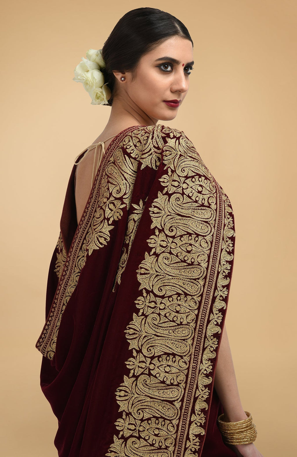Burgundy velvet saree with gold tilla aari embroidery and a woman wearing it.