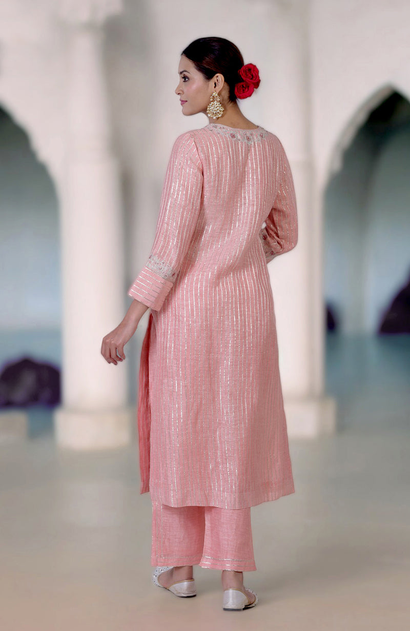 A woman models a rose pink gota and zardozi embroidered kurta set with silver sandals.