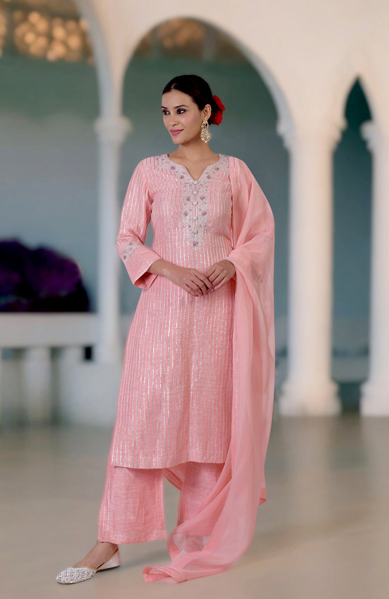 A woman models a rose pink kurta set with gota and zardozi embroidery.