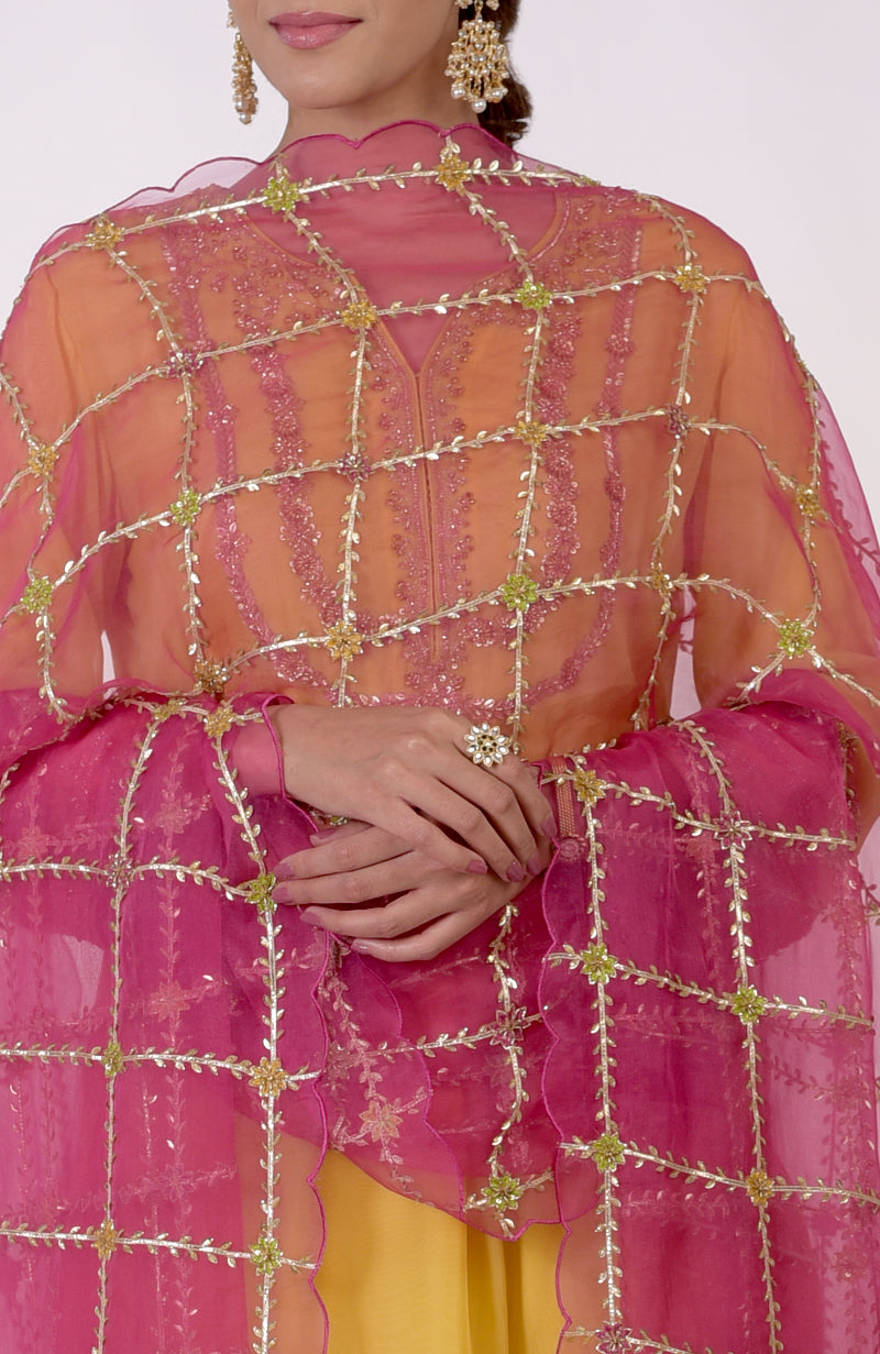 Woman in a buttercup yellow suit with a fuchsia dupatta featuring gota and zardozi work.