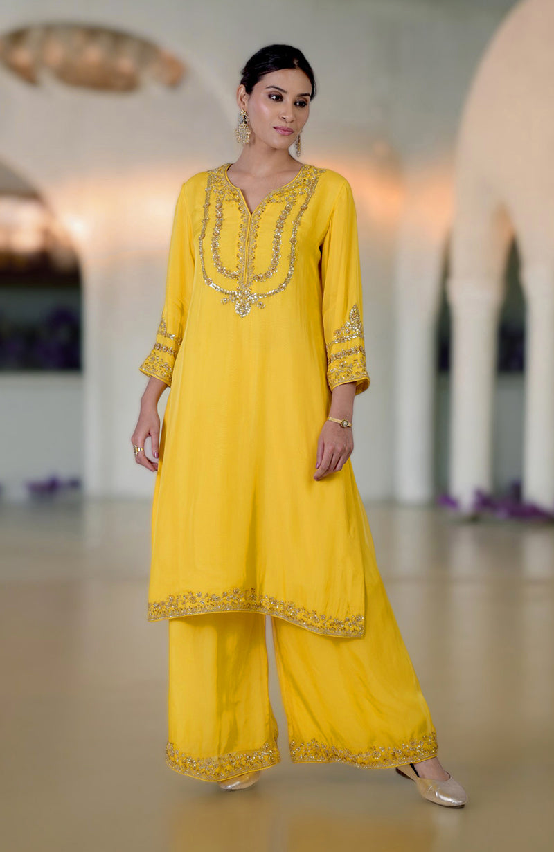 A woman models a buttercup yellow zardozi hand-embroidered suit set.