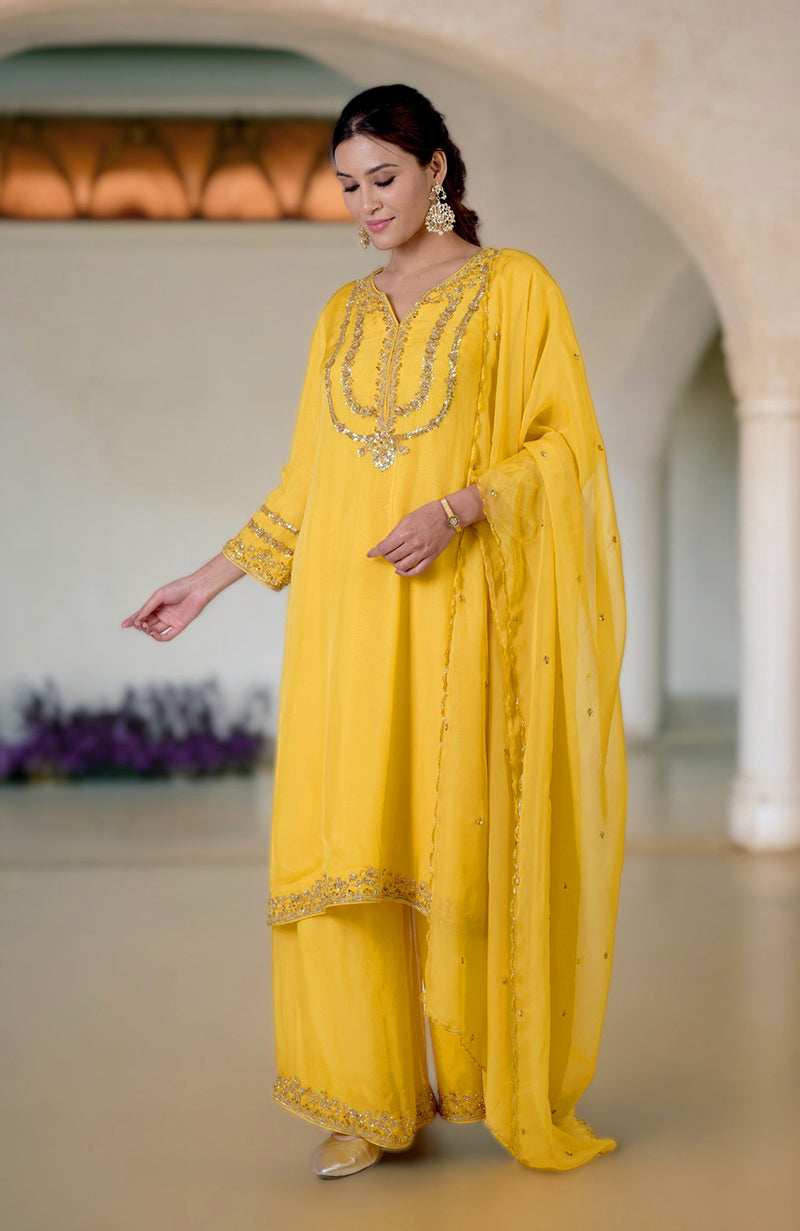 A woman models a buttercup yellow zardozi hand-embroidered suit set with a dupatta.