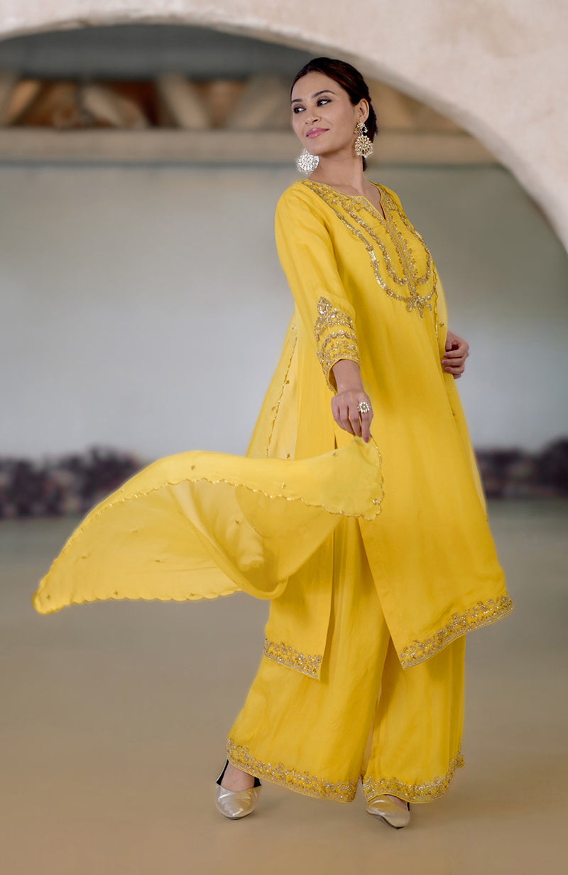 A woman models a buttercup yellow zardozi hand-embroidered suit set with a dupatta.