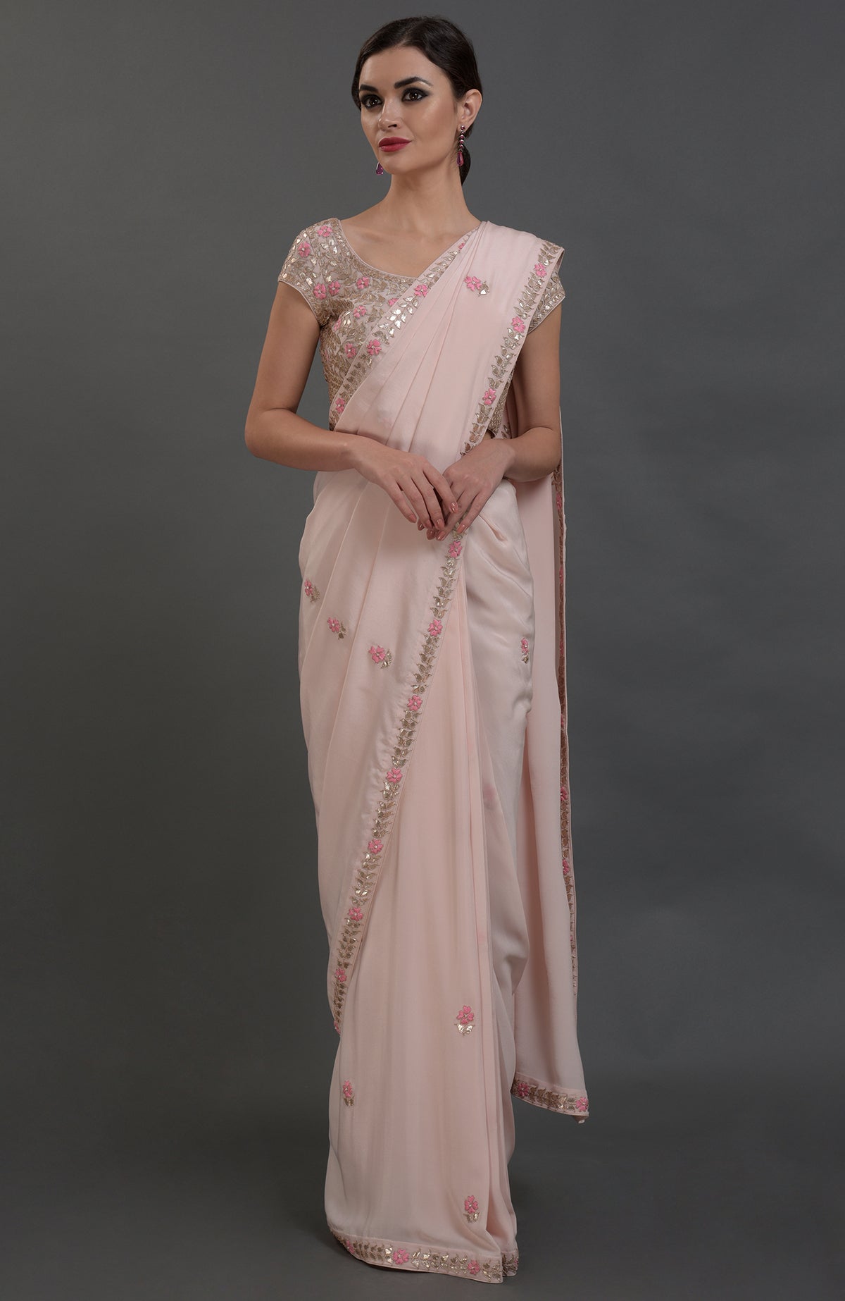 A woman models a nude pink pure crepe saree with rose gold gota patti embroidery.