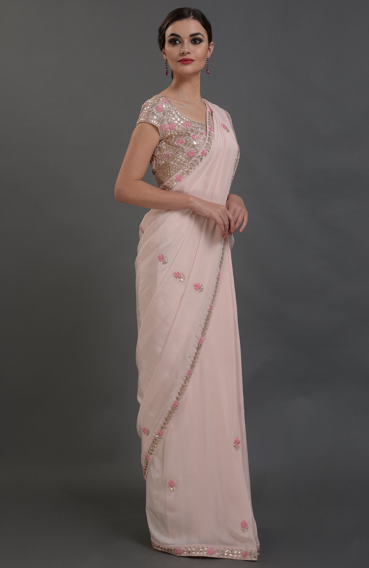 A woman models a nude pink pure crepe saree with intricate floral embroidery.