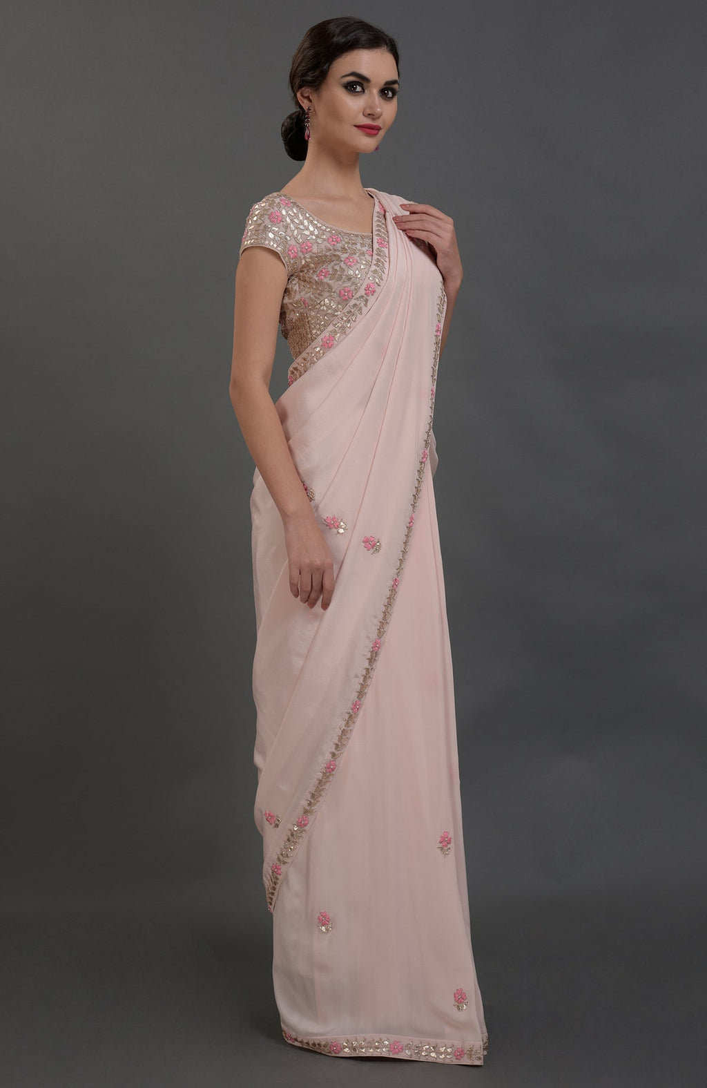 A woman models a nude pink pure crepe saree with rose gold gota patti embroidery.