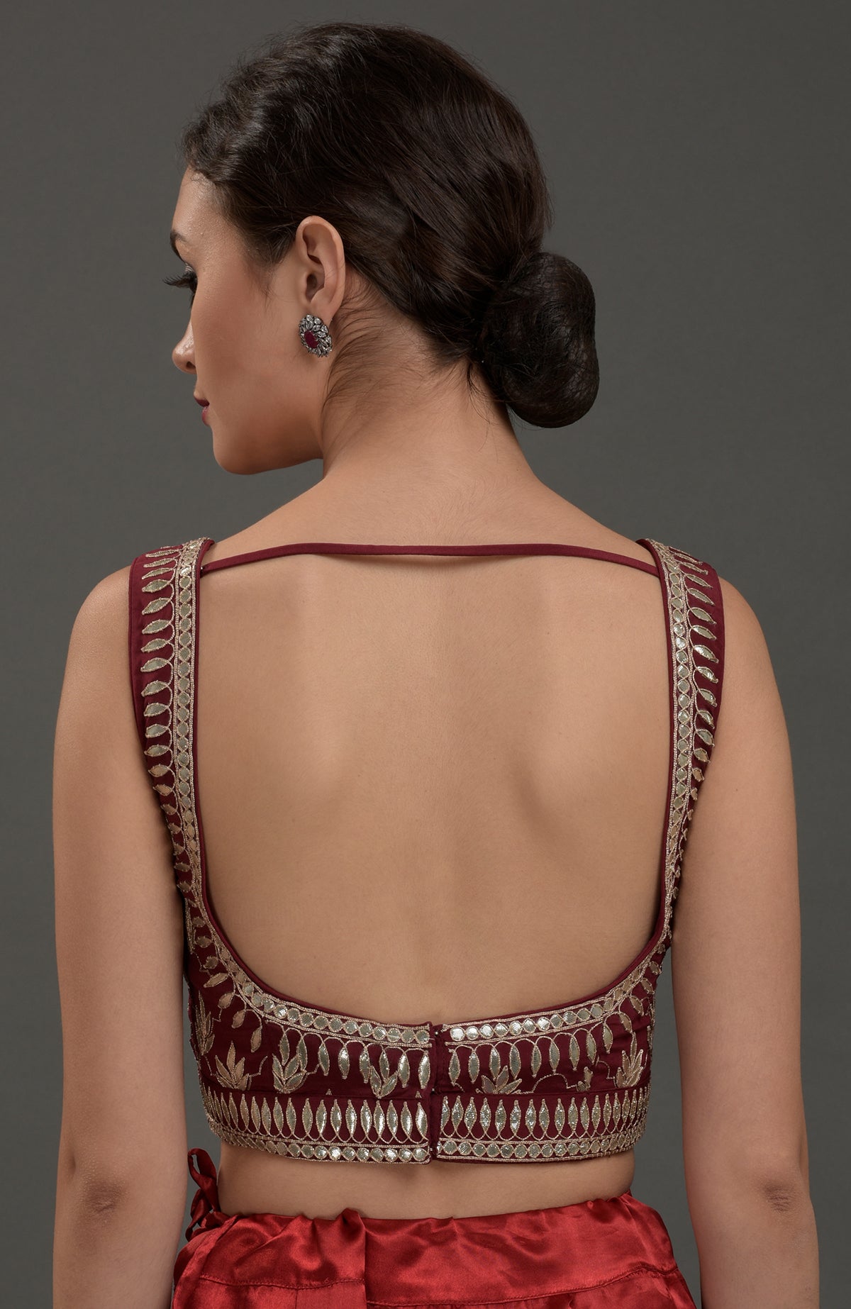 Back view of a woman in a burgundy embroidered blouse with a deep back.