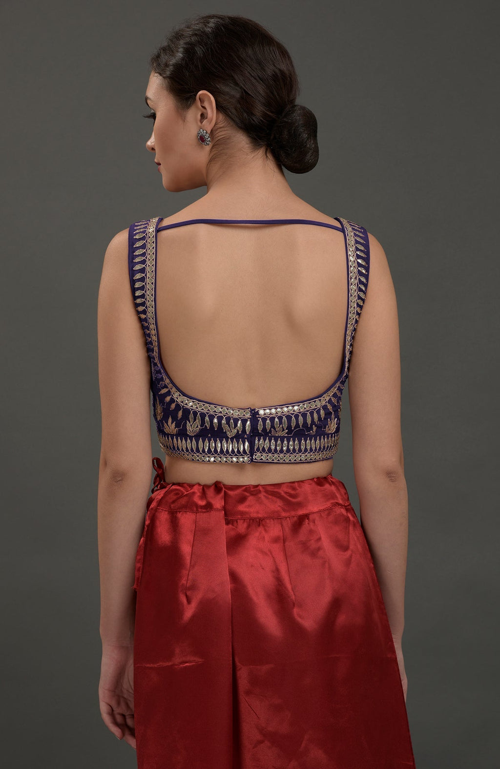 Rear view of a woman in an eclipse blue embroidered blouse and red skirt.