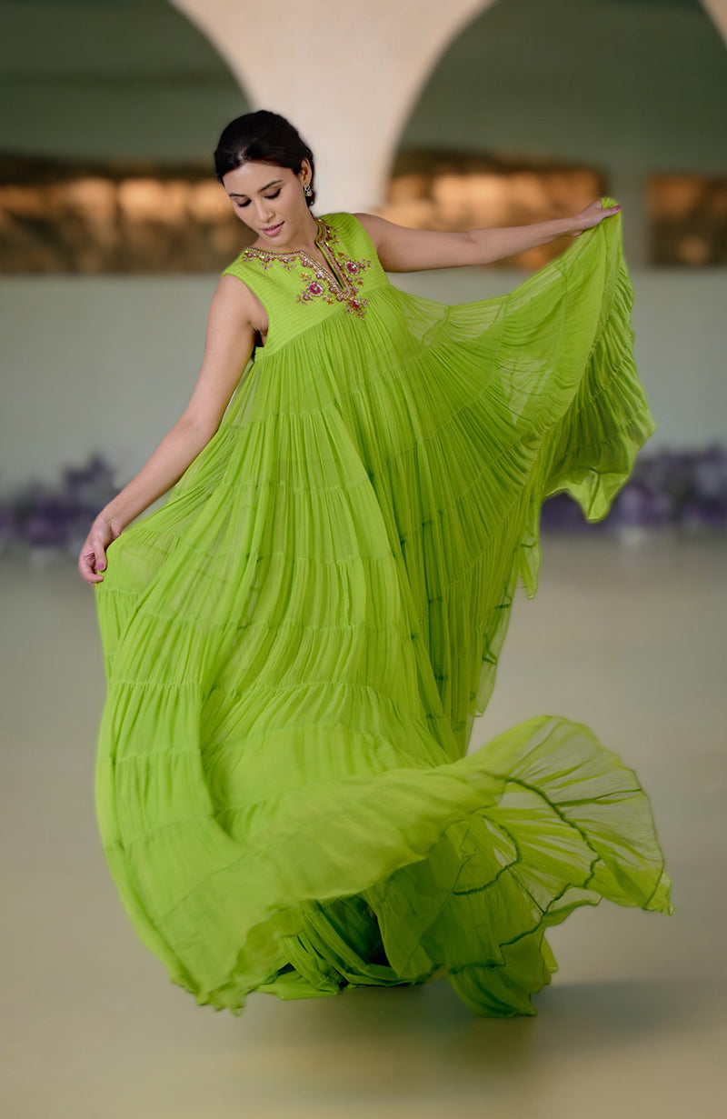 A woman in a flowing green tiered dress with zardozi embroidery on the neckline.