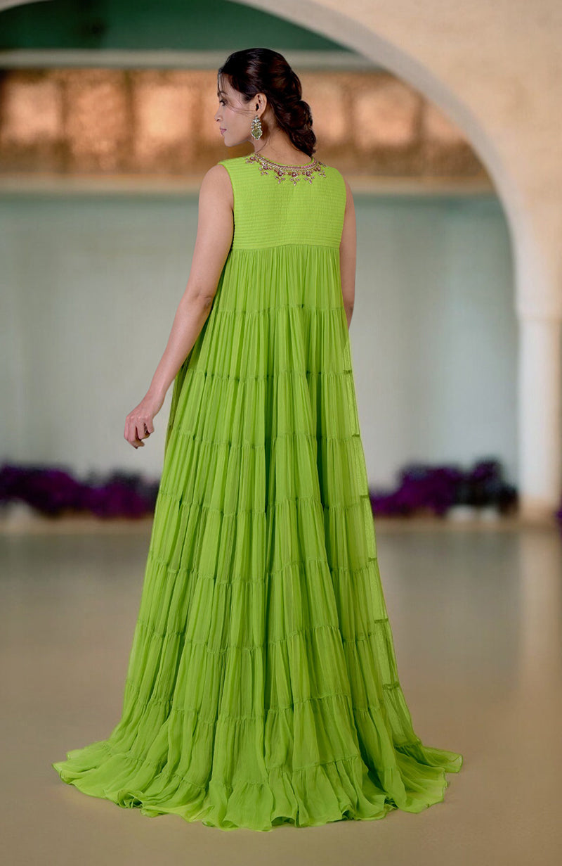 A woman models a green tiered dress with zardozi hand embroidery on the neckline.