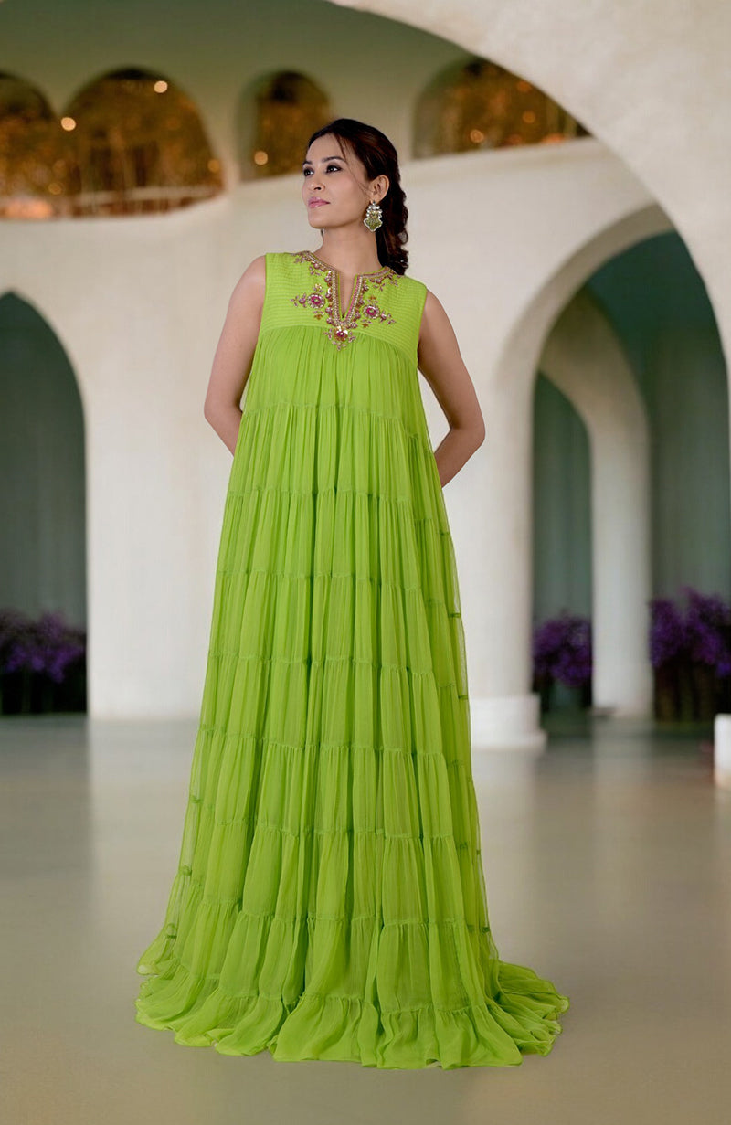 A woman models a tiered, lime green dress with intricate embroidery on the neckline.