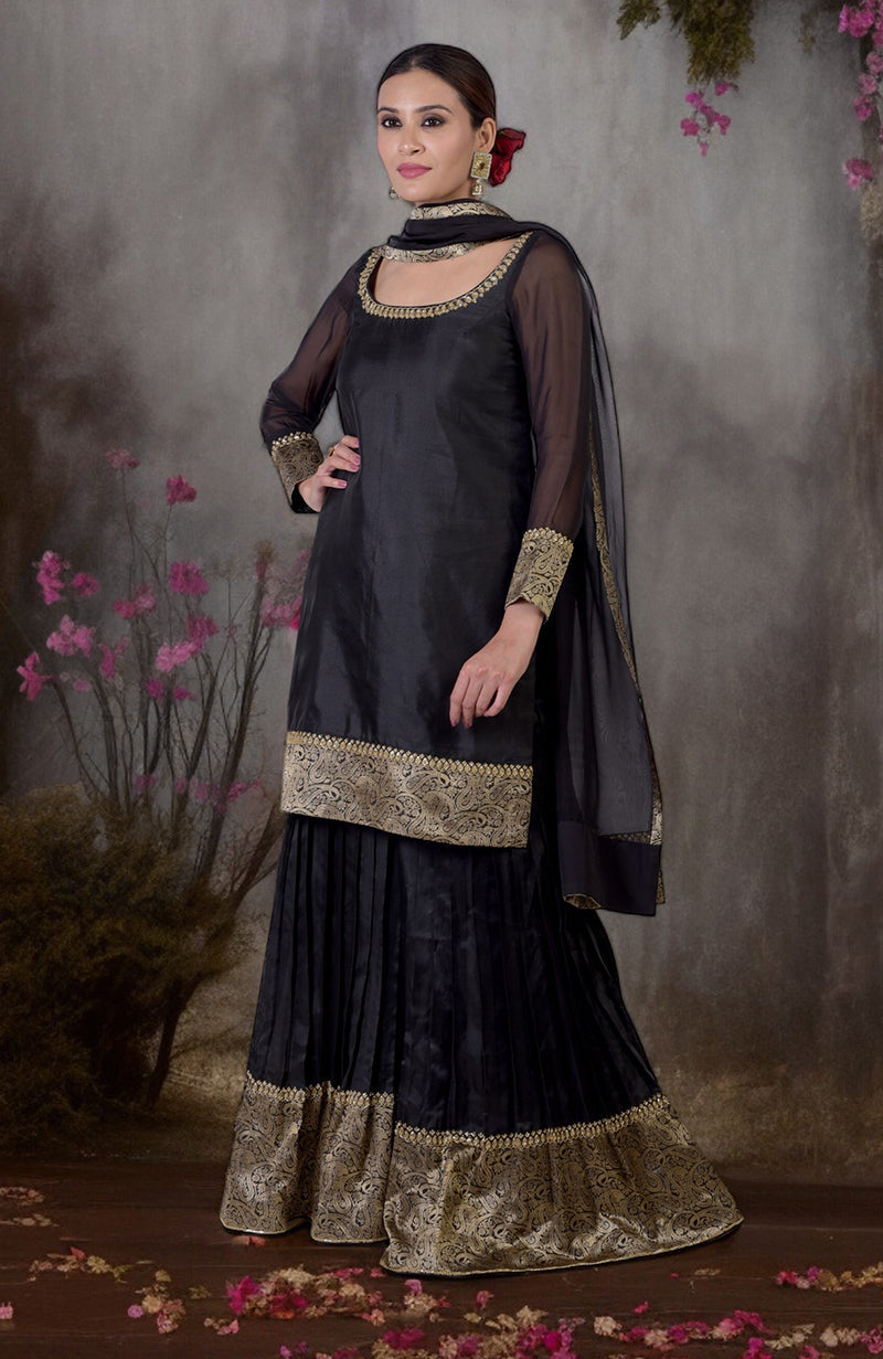 Black-gold Banarasi embroidered sharara set with a woman posing.