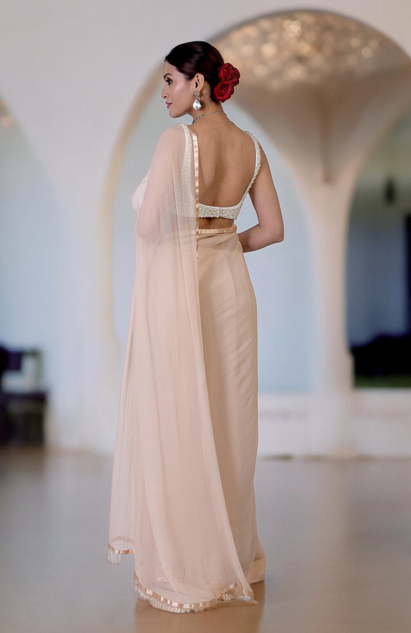 A woman in a champagne gold saree with a pearl and crystal hand-beaded blouse.