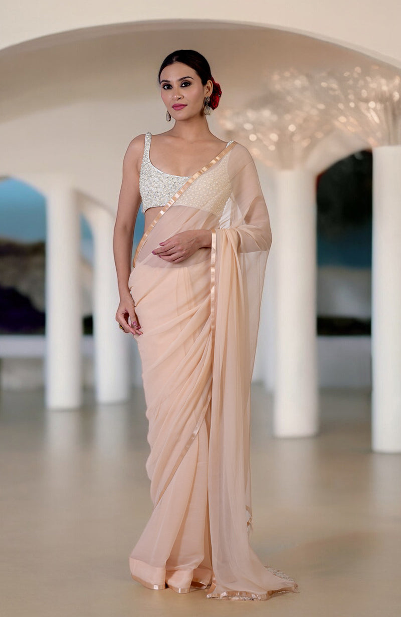 A woman models a champagne gold chiffon saree with a pearl and crystal hand-beaded blouse.