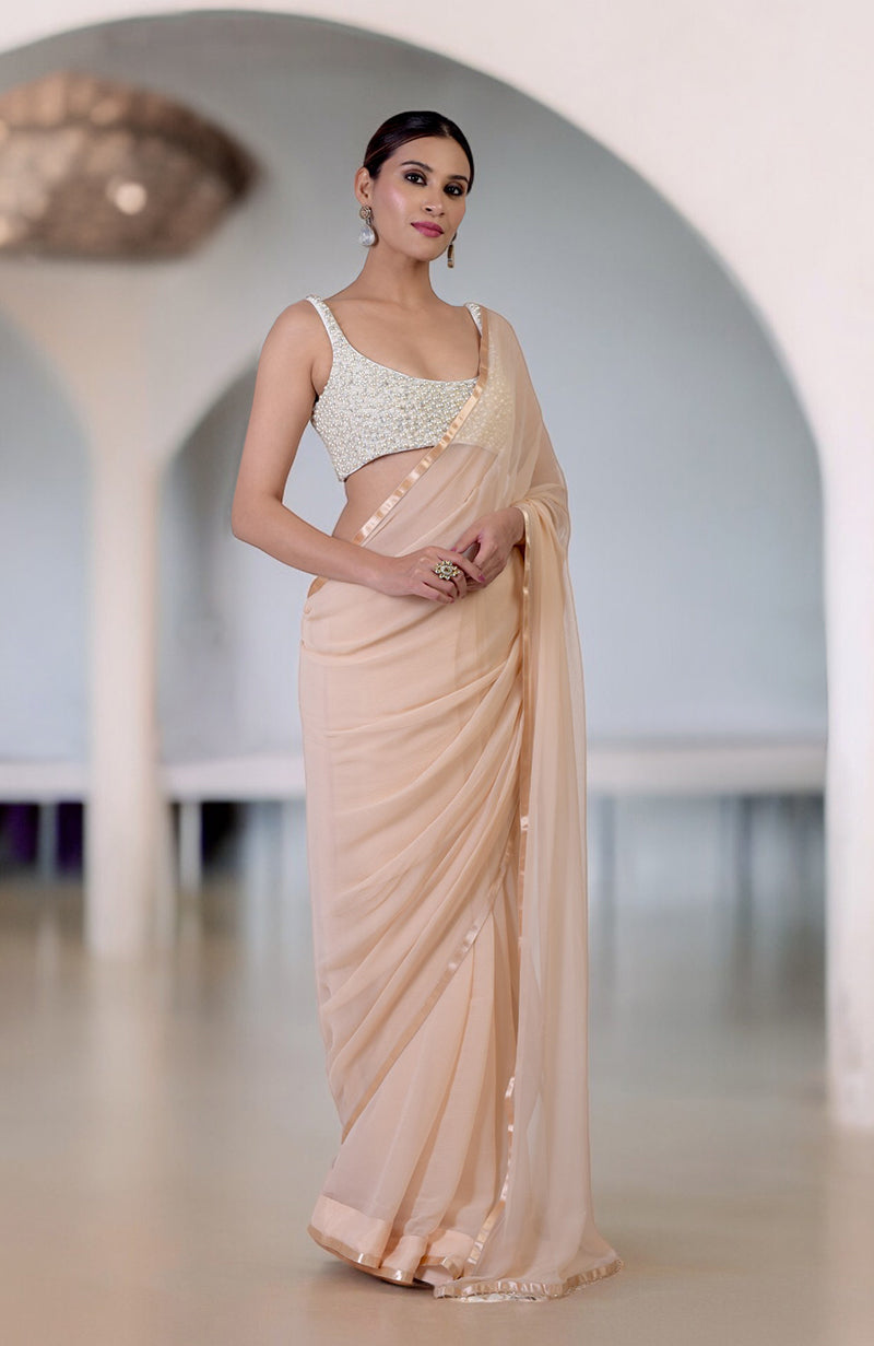 A woman models a pearl and crystal hand-beaded blouse with a champagne gold saree.