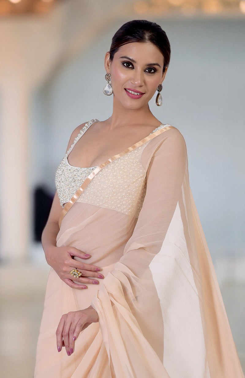 A woman in a pearl and crystal hand-beaded saree with a champagne gold drape.