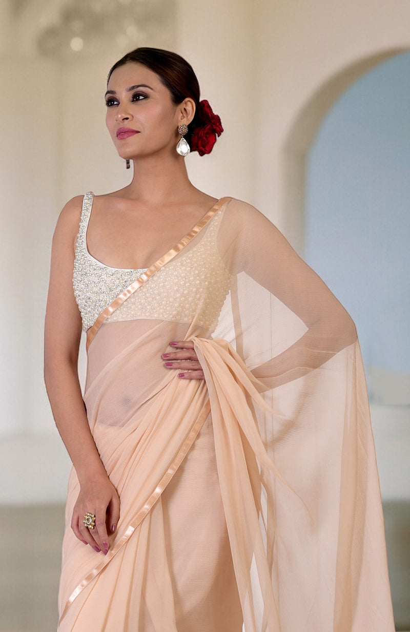 A woman models a champagne gold saree with a pearl and crystal hand-beaded blouse.