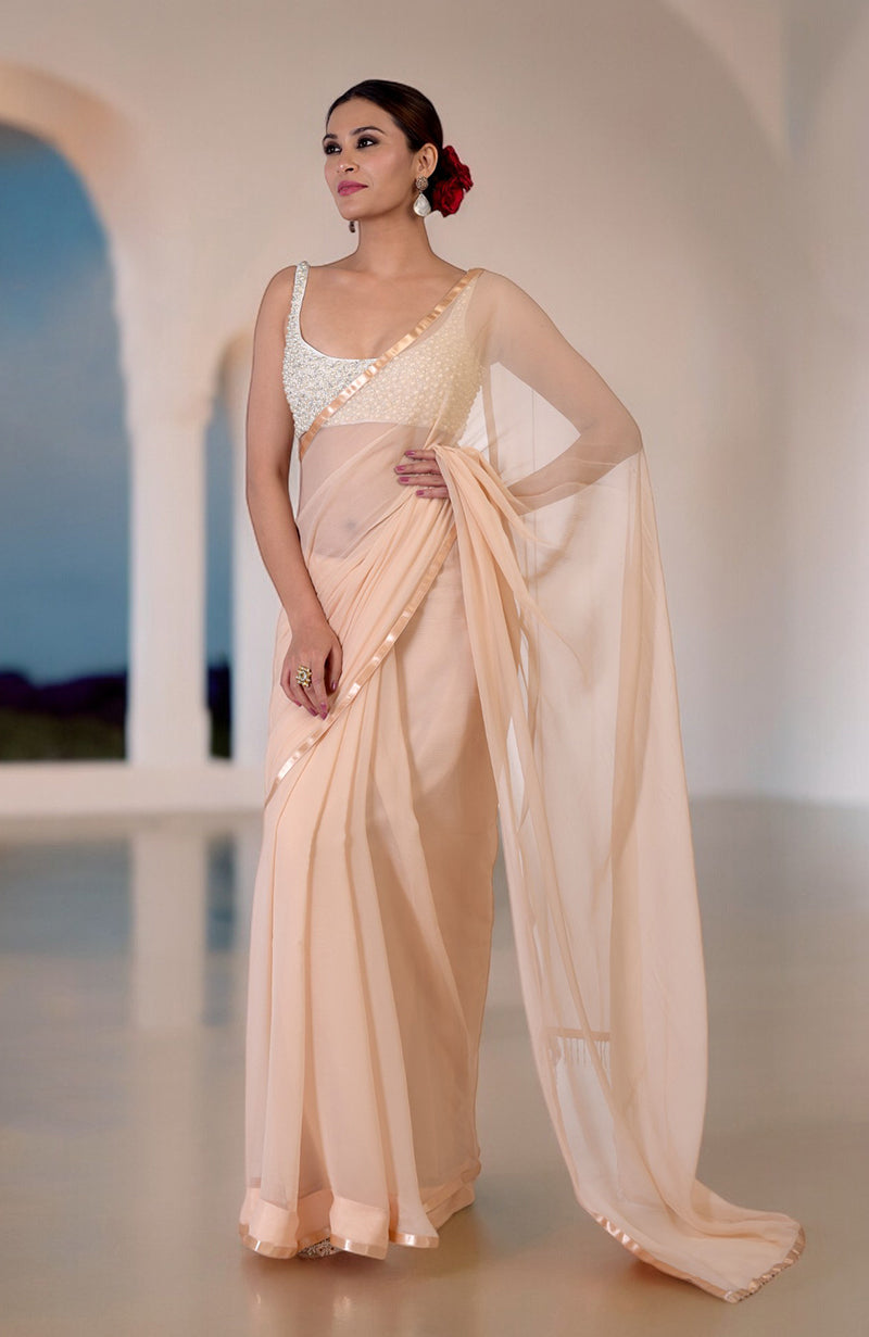 A woman models a champagne gold chiffon saree with a pearl and crystal hand-beaded blouse.