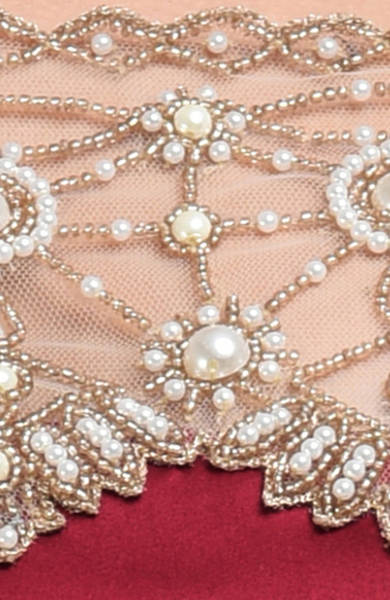 Close-up of a maroon satin silk blouse with pearl and gold bead embroidery on nude net.
