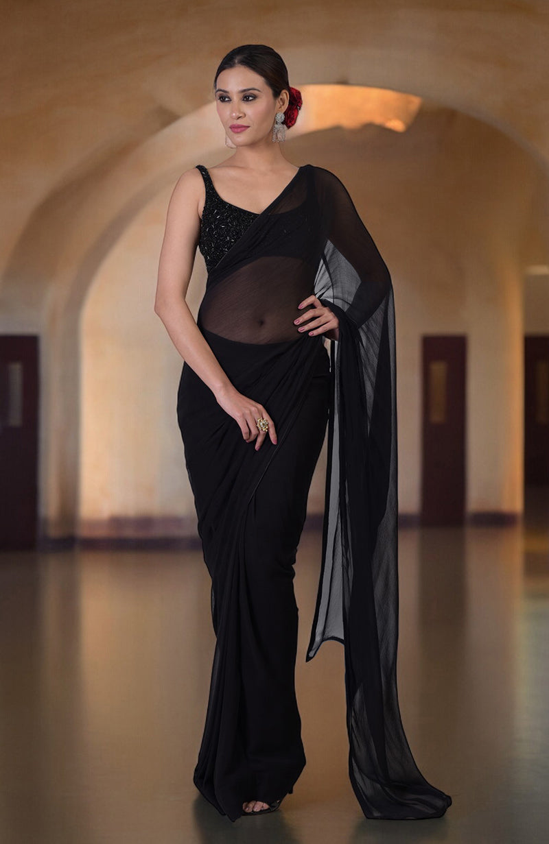 A woman models a black chiffon saree with a hand-beaded blouse.