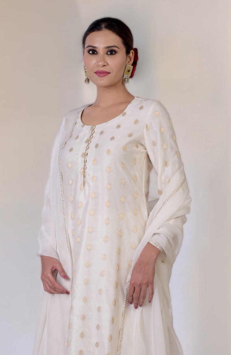 An Indian woman models an ivory Banarasi sharara set with gold embroidery.