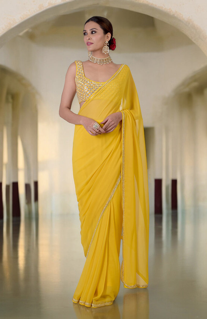 A woman models a daffodil yellow hand-embroidered saree with a beaded blouse.