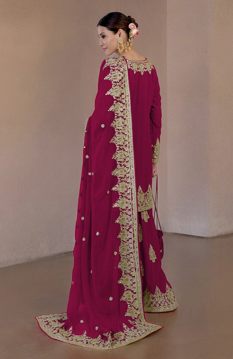 A woman models a bright rose gold embroidered sharara set with a matching potli bag.