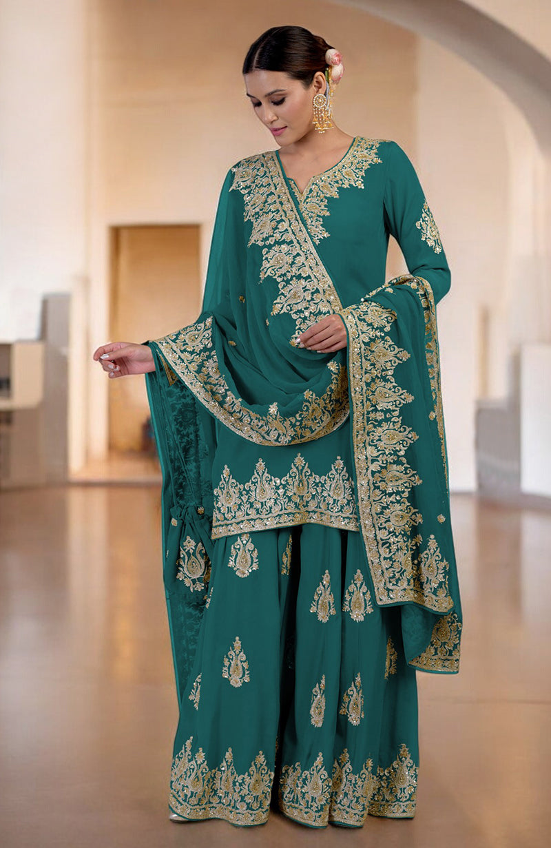 A woman models a teal sharara set with gold embroidery.